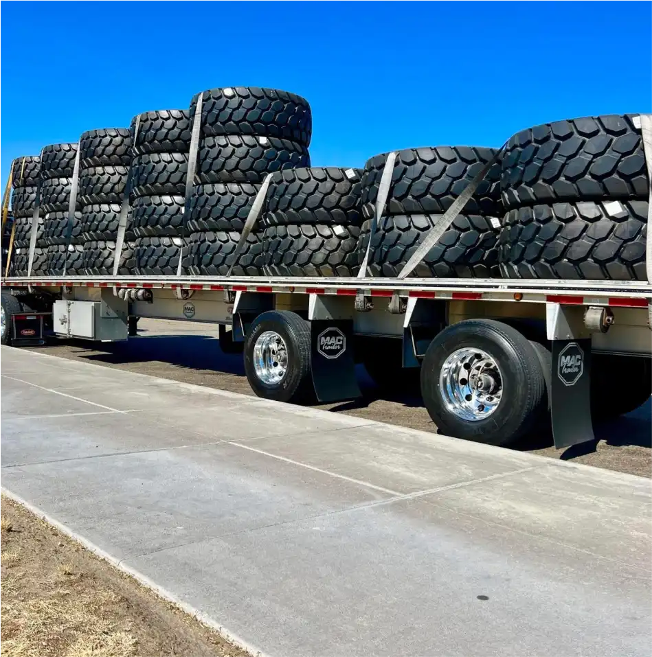 MAC Flatbed trailer loaded with large tires.