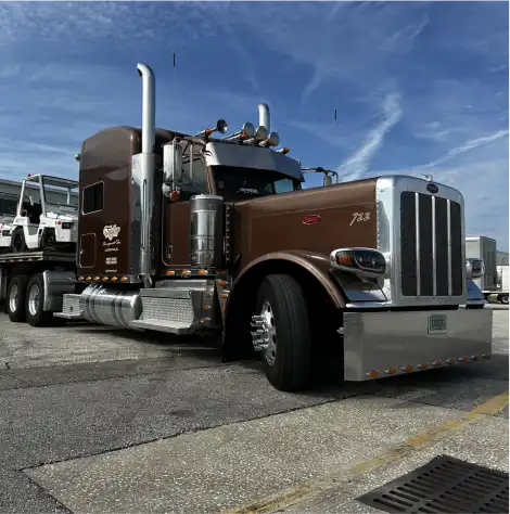 MAC Flatbed trailer loaded with golf carts. Trailer hitched to Brown Peterbilt semi truck.