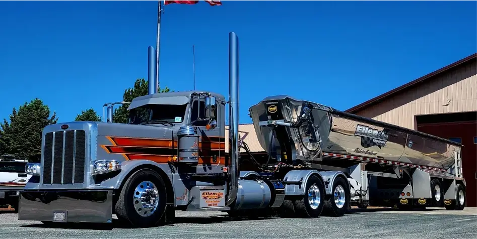 Grey Peterbilt semitruck with MAC Half Round Dump Trailer attached.